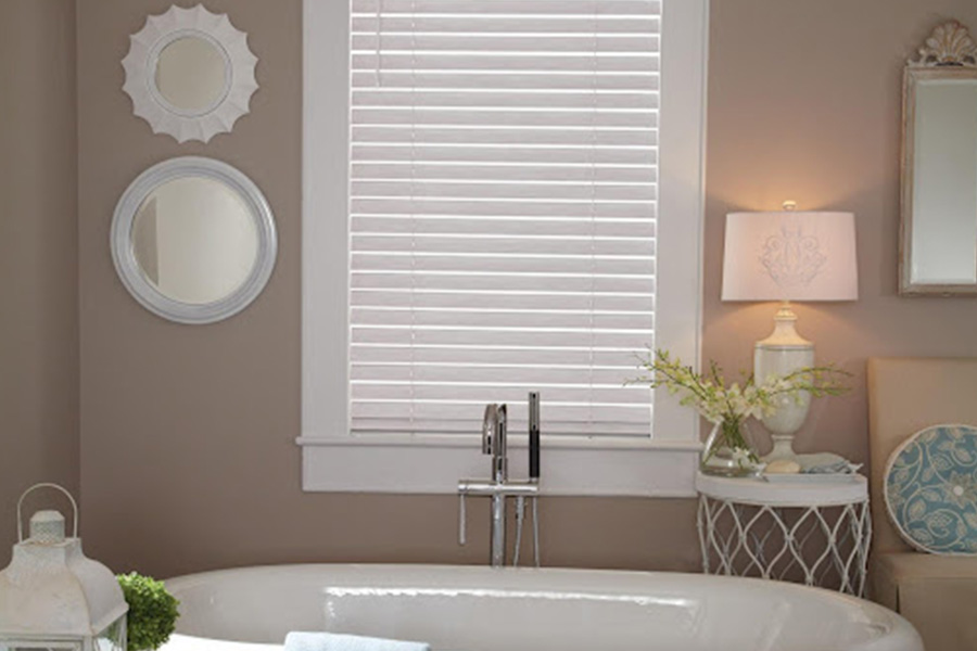 White and blue modern bathroom with two white Polywood shutter windows above a bathtub.