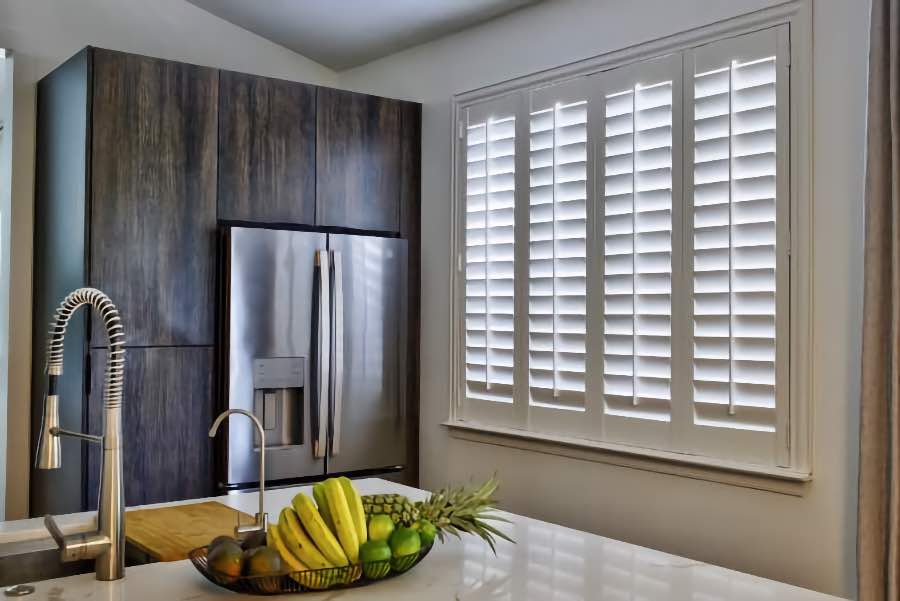 Homeowners use indoor window shutters in Bluff City when they want attractive and functional window treatments. Polywood shutters on a large kitchen window