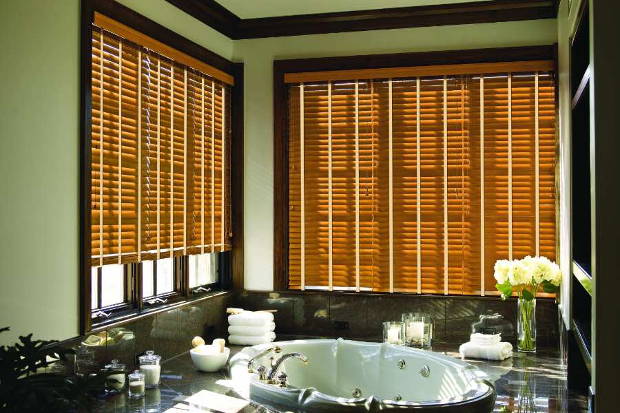 Premium quality blinds are always a stylish accent in your Bluff City home. Brown wood blinds on large windows in a green bathroom