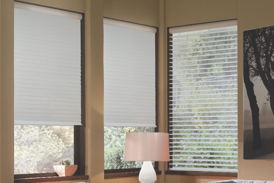Opaque motorized window shades in Bluff City keep hot UV rays out of your home. Gray motorized sheer shades on corner windows next to gray furniture