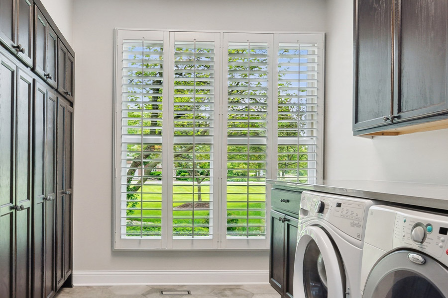 Find the perfect level of natural light for your Bluff City laundry room with interior shutters. White Polywood shutters letting light through a laundry room window