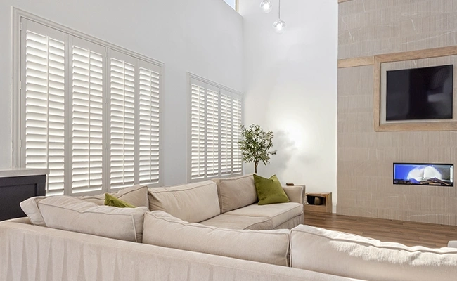Large white polywood shutters in a large living room decorated in beige