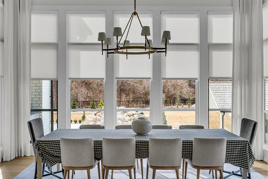 White drapes and roller shades on dining room windows